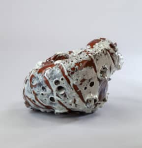 Sculpture céramique abstraite aux émaux blancs coulés et bruns rougeâtres, présentant des textures bullées et des trous.