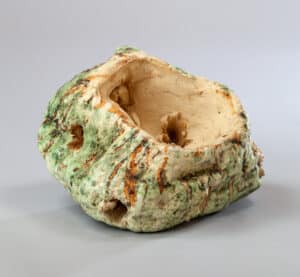 Sculpture céramique brute et texturée, évidée, avec un émail vert mousseux et des coulures brun-rouille.
