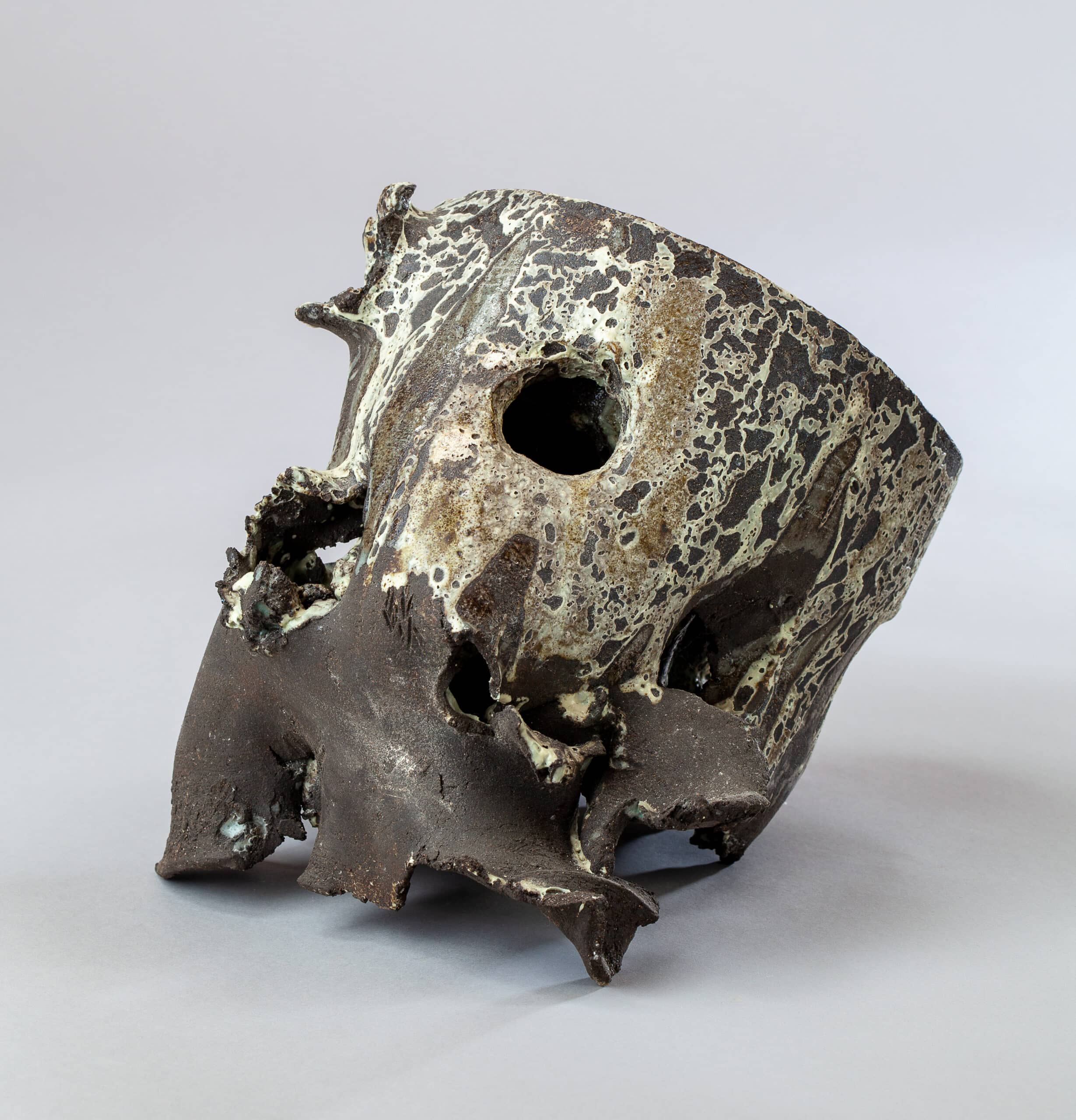 Sculpture céramique abstraite, brute et sombre, avec glaçure craquelée blanc-vert et une grande ouverture centrale.