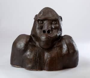 Buste sculptural en céramique brune foncée, texturée et brillante, représentant la tête et les épaules d'un gorille avec une expression sérieuse.