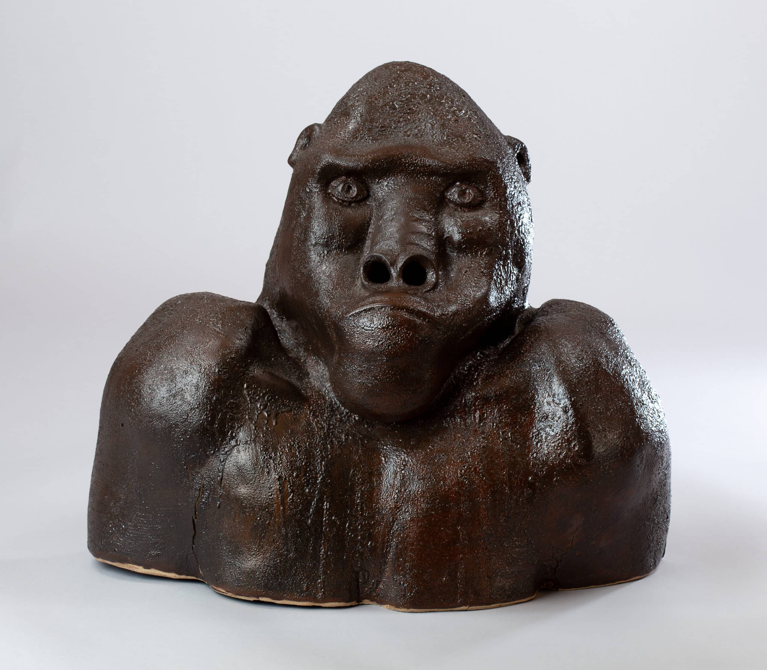 Buste sculptural en céramique brune foncée, texturée et brillante, représentant la tête et les épaules d'un gorille avec une expression sérieuse.
